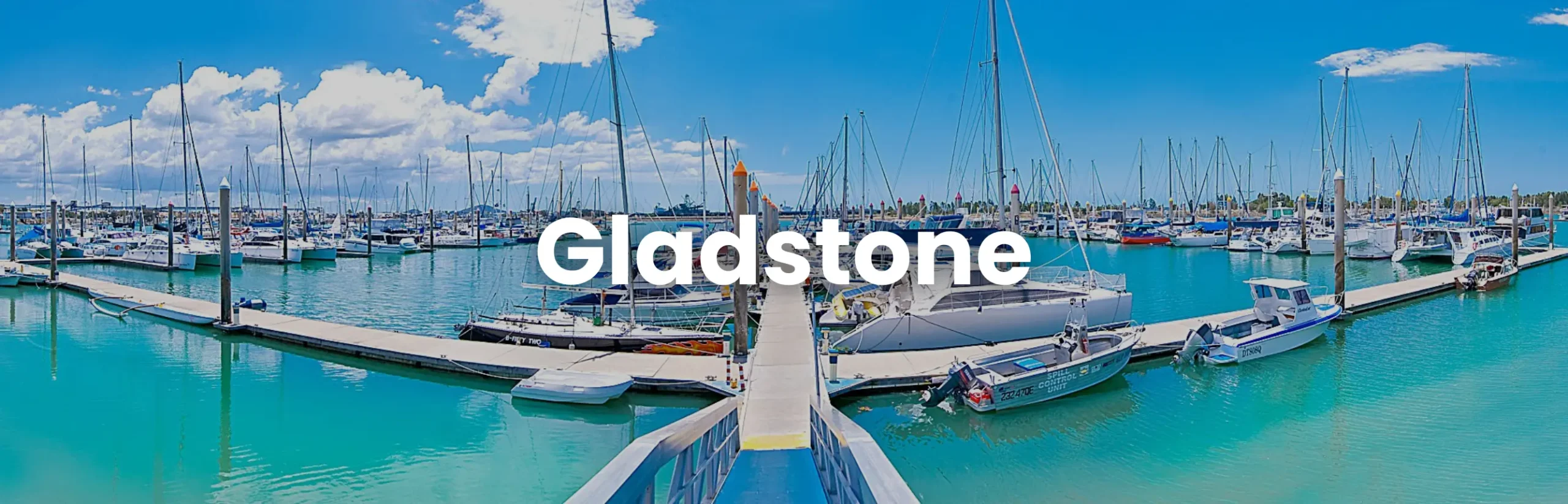 Scenic view of Gladstone Marina filled with boats under a bright blue sky, promoting the Gladstone Conference.